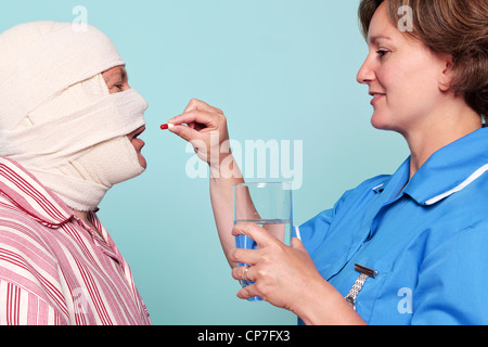 Foto von einer Krankenschwester, einem Patienten ein Medikament in Form einer Pille geben. Stockfoto