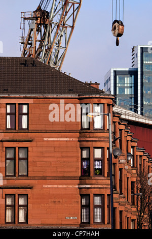 Glasgow Sandstein Mietshaus mit einem wippbar Kran aus der Werft und ein neues Bürogebäude in der Ferne. Stockfoto