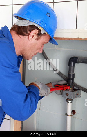 Mann, die Installation von Wasserleitungen mit einem großen Schraubenschlüssel Stockfoto