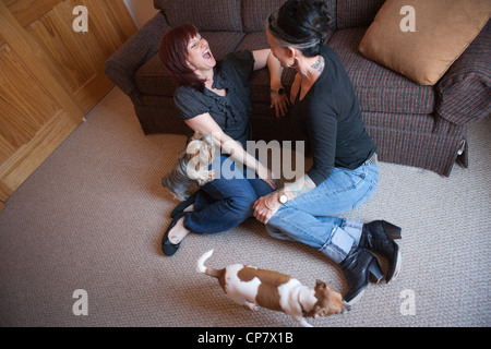 Zwei Frauen am Boden des Wohnzimmers mit zwei Hunden zusammen sprechen. Stockfoto