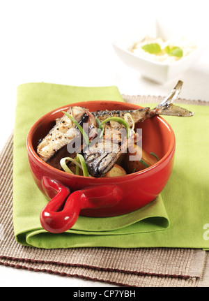 Schwenken Sie gebratene Makrele und Kartoffeln in einer roten Pfanne Stockfoto