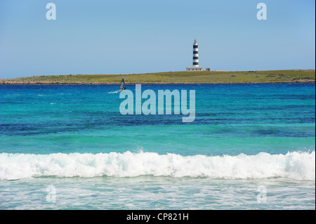 Windsurfer Segeln im türkisblauen Meer hinter dem Leuchtturm auf Illa de l'Aire, Punta Prima, Menorca, Spanien Stockfoto