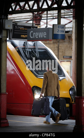 Crewe Bahnhof pro Passagier zu Fuß entlang der Plattform hinter Virgin Voyager Zug Stockfoto