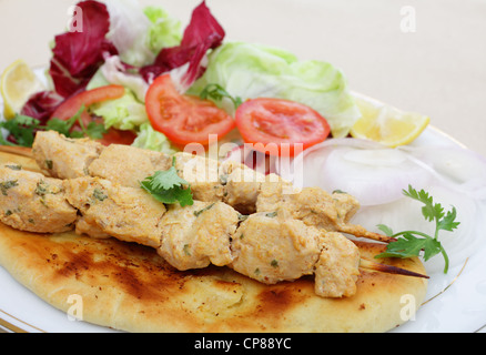Chicken Tikka Spieße serviert auf hausgemachtem Naan Fladenbrot mit Salat Stockfoto