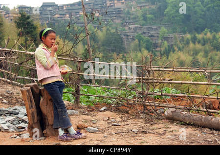 Basha Miao (Pistole Männer) junges Mädchen mit Pistole Männer Dorf im Hintergrund, Südchina Stockfoto