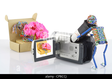 Der Spielzeug-Betreiber von einer Videokamera filmt das Spielzeug Mädchen mit einem Bouquet von rosa Blüten. Comic-Film-Produktion des Prozesses der Konzeptionierung Stockfoto