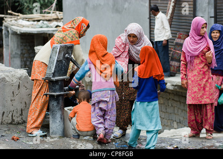 Eine Gruppe von muslimischen Frauen und Kinder füllen Eimer mit Wasser in Kargil Stadt, Bundesstaat Jammu und Kashmir, Indien Stockfoto