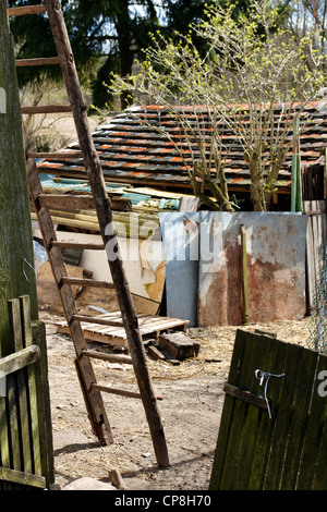 Blick in einen Hinterhof Bauernhof mit einer alten Holzleiter hinauf in die Scheune, in der Nachmittagssonne liegend. Stockfoto