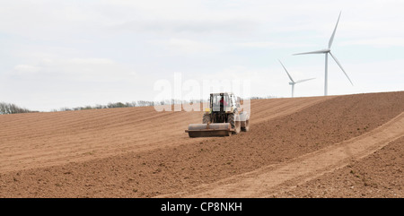 Traktor arbeitet ein Acker mit Windkraftanlagen im Hintergrund, Fullabrook Windpark North Devon, UK Stockfoto