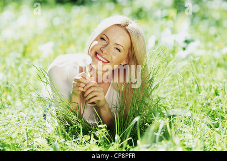 Mädchen mit einem Löwenzahn in der Hand liegend auf dem Rasen Stockfoto