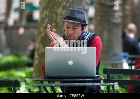 Ein Mann arbeitet auf seinem Apple Macbook Pro Laptop-Computer im Bryant Park in New York City. Stockfoto