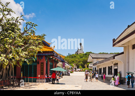 Besucher in der Hauptstraße von Ngong Ping auf Lantau Island, Hong Kong, von der Tian Tan Buddha-Statue dominiert. Stockfoto