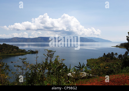 Eine lange weiße Wolke übergibt der ruhigen Oberfläche des Kivu-Sees in Ruanda. Stockfoto