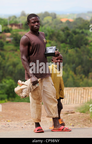 Ein junger Mann hält einen Radio auf einer ländlichen Straße in der südlichen Provinz von Ruanda. Stockfoto