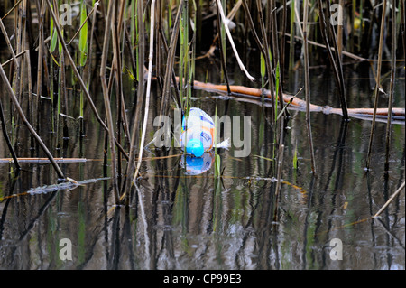 Leer und weggeworfenen Kunststoff trinkt Flasche unter Schilf in einem See schwimmen. Stockfoto