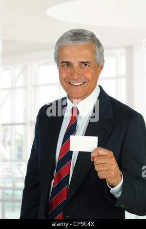 Lächelnd Mitte Alter Geschäftsmann in modernen Büroumgebung Leere Visitenkarte durchhalten. Hochformat. Stockfoto