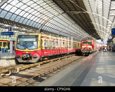 Die Deutsche Bahn in Berlin - Spandau. Ein Hauptzweig Personenzug abfahren, mit einer S-Bahn neben Innenraum warten Stockfoto