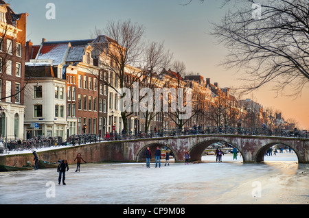 Skater genießen das Eis an einem Winterabend an der Keizersgracht in Amsterdam, Niederlande. Stockfoto