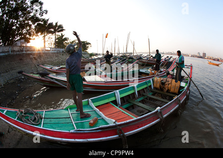 Junger Mann werfen Kraftstoffbehälter, stehend auf einem Fisch-Boot in Dallah Hafen Yangon River, Yangon Burma Myanmar Stockfoto