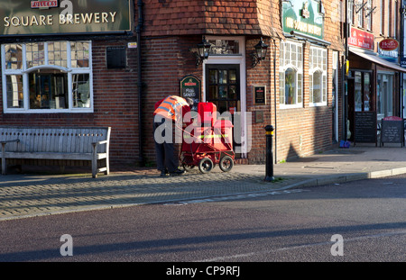 Royal Mail Postbote liefert Post vom roten Postamt Handwagen in Petersfield, Hampshire, UK Stockfoto