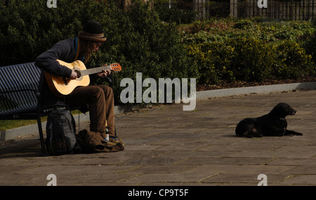 Straßenmusiker spielen der Gitarre auf einer Bank sitzen. London. England. VEREINIGTES KÖNIGREICH. Stockfoto