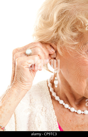 Nahaufnahme der senior Frauenhand einfügen ein Hörgerät in ihr hören. Stockfoto