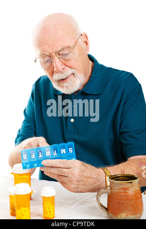 Senior woman verwendet einen Pille-Organizer, seine Medikamente für die Woche vorzubereiten. Weißen Hintergrund. Stockfoto