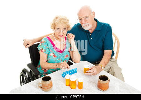Älteres paar frustriert über Gesundheitsfragen, am Tisch von Tablettenfläschchen umgeben. Isoliert auf weiss. Stockfoto