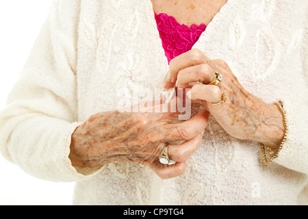 Ältere Frau arthritischen Händen kämpfen, um ihren Pullover-Taste. Stockfoto