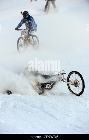 Ein Mountainbiker stürzt während des Rennens auf Schnee in Saas Feegletscher-Bike-Event in der Schweiz. Stockfoto