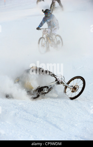 Ein Mountainbiker stürzt während des Rennens auf Schnee in Saas Feegletscher-Bike-Event in der Schweiz. Stockfoto