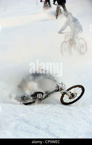 Ein Mountainbiker stürzt während des Rennens auf Schnee in Saas Feegletscher-Bike-Event in der Schweiz. Stockfoto