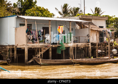 Riverside Häuser unterstützt von Stelzen, Cai Be, Mekong River Delta, Vietnam Stockfoto