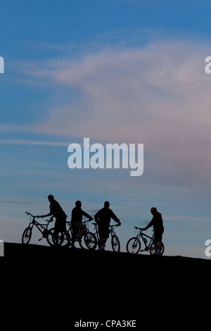 Gruppe von Mountainbikern auf Hügel bei Dämmerung, England, UK Stockfoto