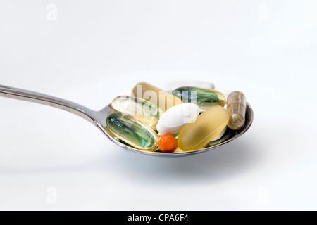 Auswahl an Vitaminen (Omega-3, Co-Enzym Q10, Pfefferminze, Chondroitin, Ginkgo und Ginseng) auf Löffel auf weißem Hintergrund. Stockfoto