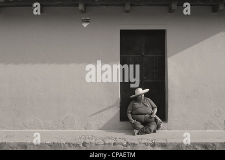 Guatemala Antigua Mann mit Sombrero-Hut sitzt durch bunte Wand cobble stone Straßenszene der UNESCO Stockfoto