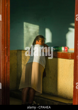 Eine kubanische Frau mittleren Alters Hispanic lehnt sich gegen einen Zähler mit ihren Flaschen, im späten Nachmittag Licht in Viñales, Kuba zurück. Stockfoto