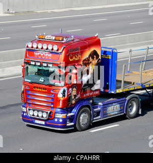 Johnny Cash LKW-Art-Grafiken Seitenansicht von Scania Sattelzugmaschine mit Sattelzugmaschine und Flachlader, die auf der britischen Autobahn in England fahren Stockfoto