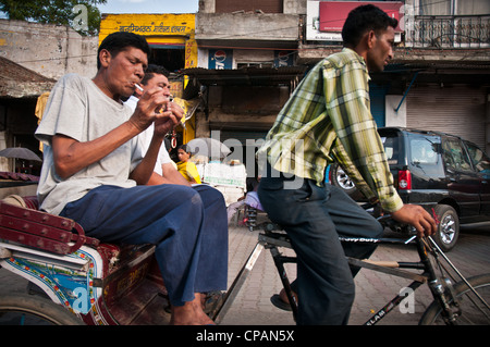 Ein Mann versucht, sich eine Zigarette anzuzünden, während der Fahrt in einer Fahrrad-Rikscha in der Nähe von Amritsar, Indien. Stockfoto