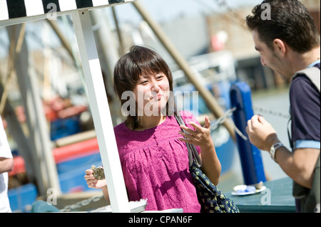 Junges Paar essen Austern in Whitstable Hafen, Kent, England, UK Stockfoto