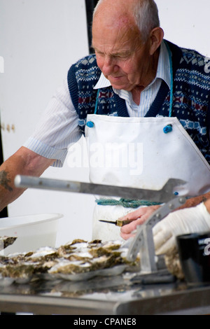 Mann Vorbereitung Austern, Whitstable Hafen Fischmarkt in Kent, England, UK Stockfoto