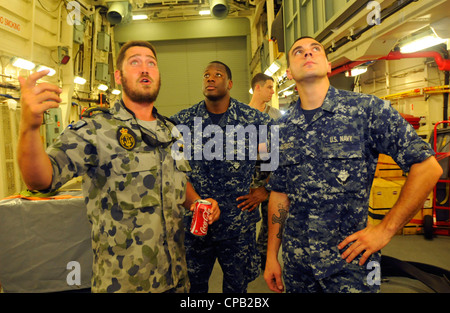 Der Schiffstechniker Matt Bennett bespricht die Hangarbucht der Fregatte HMAS Ballarat (FF 155) der Royal Australian Navy und gibt Seglern, die dem Flaggschiff der US-Flotte USS Blue Ridge (LCC 19) zugeordnet sind, eine Schiffsrundfahrt. Blue Ridge führte einen Austausch zwischen den Schiffen durch, um sein Engagement für regionale Partnerschaften und die Förderung der Beziehungen zu demonstrieren. Stockfoto