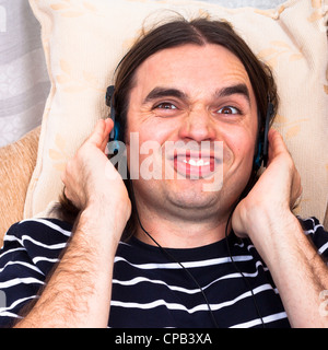 Lustige Jüngling mit Kopfhörern hören Musik auf Sofa. Stockfoto