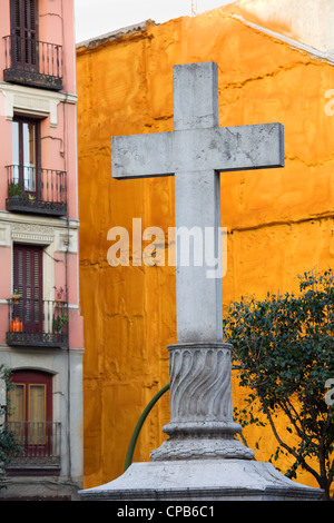 Steinernes Kreuz machte im Jahre 1738 gegen eine lebendige orange Wand an der Plaza de Puerta Cerrada in der Altstadt von Madrid in Spanien Stockfoto