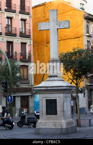 Steinernes Kreuz machte im Jahre 1738 gegen eine lebendige orange Wand an der Plaza de Puerta Cerrada in der Altstadt von Madrid in Spanien Stockfoto