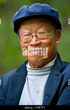 Eine ältere chinesische Mann gekleidet in traditioneller Kleidung mit Runde Brille Pose für die Kamera in Pingliang. Stockfoto