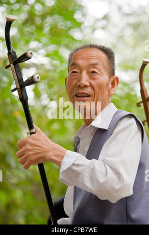 Ein chinesischer Musiker spielen das traditionelle chinesische Instrument, Erhu - chinesische Violine, am frühen Morgen in einem Park in Pingliang. Stockfoto