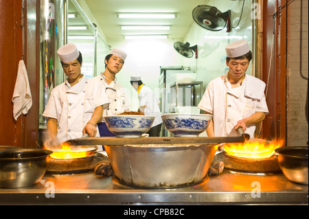 Chinesische Köche kochen über eine traditionelle Gas brennenden Ofen und Wok in einem Restaurant in Muslim Street (Huimin Jie) in Xian. Stockfoto