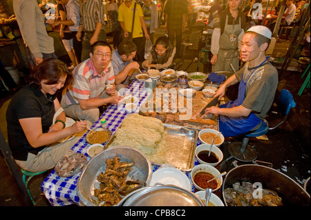 Eine Gruppe von einheimischen Essen Schaf Kopf und Magen Snack auf dem bekannten Zhengning Straße Essen street Nachtmarkt in La Stockfoto