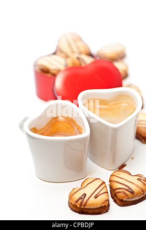 herzförmige Creme Cookies auf rotes Herz Metallbox und paar Espresso Kaffeetassen Stockfoto